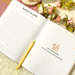 May include: An open journal with lined pages and the text "letter to you" on the left page. The right page has the number "18" with the text "your 18th birthday not the end, just the beginning". A yellow pen rests on the pages.