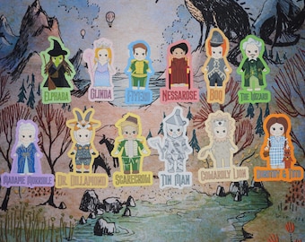 May include: A collection of colorful die-cut stickers featuring characters from The Wizard of Oz, including Elphaba, Glinda, and Dorothy. Each sticker has a unique design and name label. The background depicts a stylized landscape.