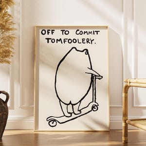 Może przedstawiać: Oprawiony wydruk artystyczny z kapryśną ilustracją niedźwiedzia na skuterze. Czarna grafika liniowa jest osadzona na kremowym tle, z napisem "OFF TO COMMIT TOMFOOLERY" pogrubioną czcionką.