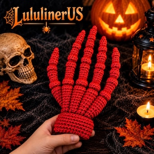 May include: A bright red crocheted hand sculpture featuring elongated, segmented fingers that mimic a skeletal structure. The item is crafted with a dense, textured yarn stitch and includes a wide, solid cuff at the base for support.