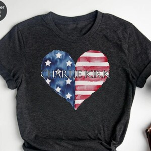 A black t-shirt with a heart-shaped design featuring the text "CHARLIE KIRK" and an American flag pattern.