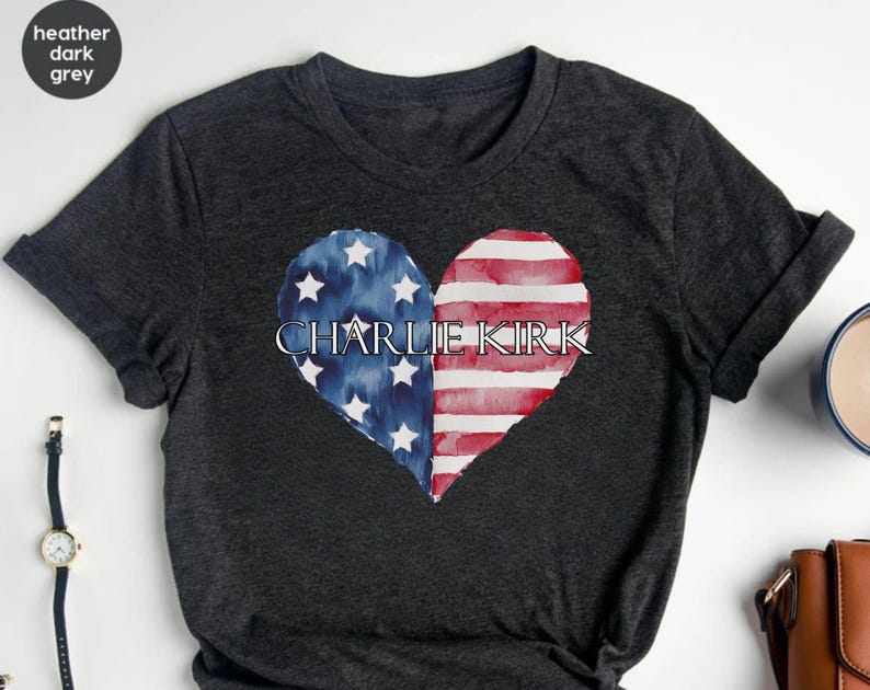 A black t-shirt with a heart-shaped design featuring the text "CHARLIE KIRK" and an American flag pattern.