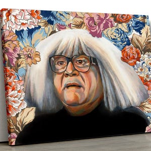 Könnte beinhalten: Leinwanddruck mit einem Porträt einer Person mit weißem Haar und Brille, vor einem floralen Hintergrund mit roten, rosa und blauen Blumen. Die Person trägt ein schwarzes Oberteil.