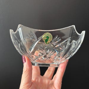 May include: Clear crystal bowl with a square base and a scalloped rim. The bowl features a cut glass design with a seahorse sticker. The bowl is likely used for serving or display.