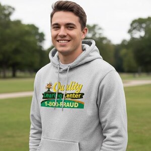 May include: A light gray hoodie with a front pocket and a drawstring hood. The hoodie features a graphic with the words "Quality Learning Center" and the phone number "1-800-FRAUD" in yellow, green, and black.