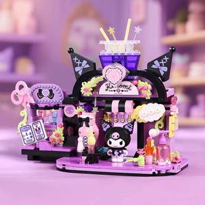May include: A purple and black building block set depicting a cartoon character. The set includes a shop facade with bows, flowers, and a sign reading "Kuromi". The design is playful and features various decorative elements.