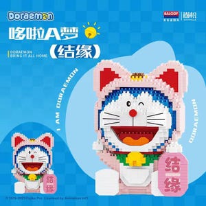 May include: A Doraemon block figure in a pink costume with red details. The figure has a blue body, white face, and a red nose. The image includes the text "Doraemon" and "Bring it all home".