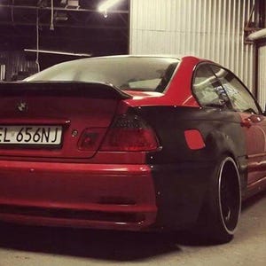 May include: A two-door car with a red and black colour scheme. The rear of the car is red, while the side panel is black. The car has a spoiler and black wheels.