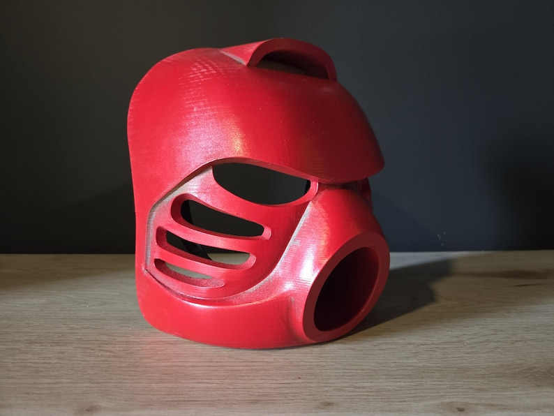 Puede incluir: Un casco r&iacute;gido de color rojo brillante moldeado que presenta una secci&oacute;n superior lisa y redondeada, un borde prominente tipo visera y una serie de tres ranuras de ventilaci&oacute;n horizontales en el lateral. El frente incluye una gran abertura circular.