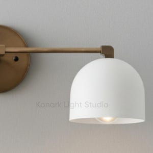 Mid century modern brass vanity light mounted above bathroom mirror, double wall sconce lighting fixture for modern bathroom decor