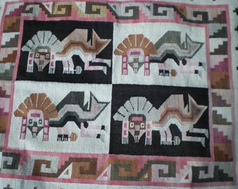 May include: A woven textile featuring a repeating pattern of stylized animal figures in black, white, and shades of brown and pink. The design is divided into squares with a border of geometric shapes.