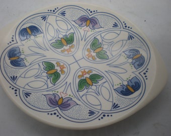 May include: A white ceramic serving dish with a blue and green floral design. The dish has a scalloped edge and two handles.