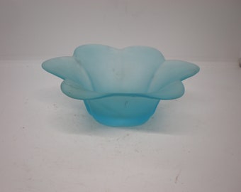 Puede incluir: Un tazón de vidrio azul claro con un diseño en forma de flor. El tazón está esmerilado y tiene una superficie lisa y redondeada.