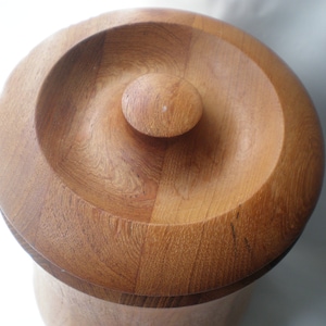 May include: A wooden ice bucket with a round, lidded top. The lid has a small, round knob in the center.