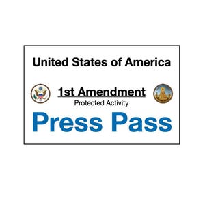 Puede incluir: Un pase de prensa rectangular blanco con el texto "United States of America" en la parte superior. Debajo, se lee "1st Amendment Protected Activity" y "Press Pass" en azul. El pase incluye dos sellos circulares.