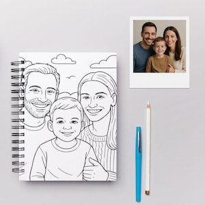 May include: A spiral-bound notebook with a black and white illustration of a family of three. A color photograph of the same family is next to the notebook. A blue pen and a white pencil are also on the surface.