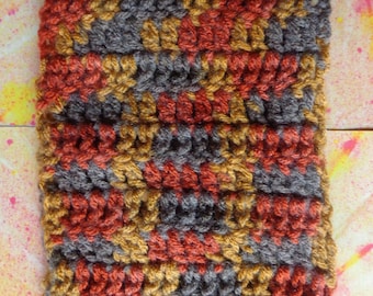 May include: Close-up of a crocheted fabric with a repeating pattern of brown, orange, and gold yarn.