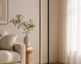 May include: A tall, slender floor lamp featuring a matte black rectangular frame with an integrated vertical LED light strip. The lamp is anchored by a solid black cubic base and includes a thin black power cord extending along the floor.
