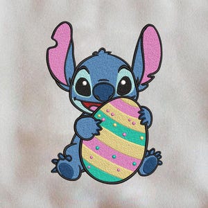 May include: Cream-colored sweatshirt featuring a blue cartoon character holding a colorful Easter egg. The character has large ears and is smiling. The egg has pink, yellow, and green stripes.