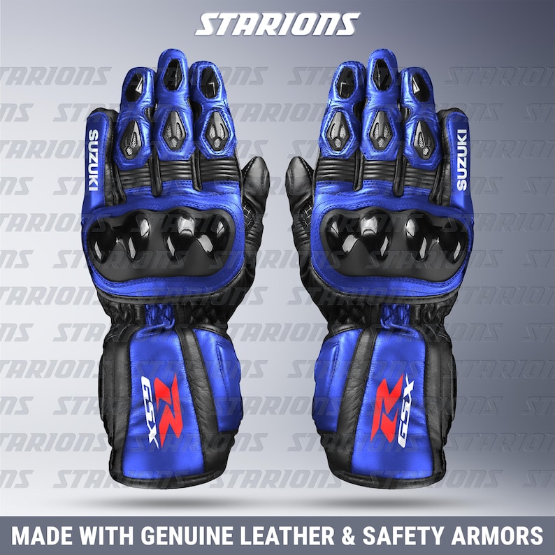 Może przedstawiać: Para niebiesko-czarnych rękawic motocyklowych z logo Suzuki. Rękawice mają ochronny pancerz na kostkach i nadgarstku. Tekst "MADE WITH GENUINE LEATHER & SAFETY ARMORS" znajduje się na dole.