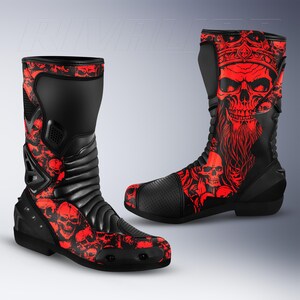 Puede incluir: Un par de botas de motocicleta negras y rojas con un estampado gráfico de una calavera con corona en el lateral. Las botas incluyen paneles negros texturizados, secciones reforzadas en el talón y la puntera, y un patrón de calaveras repetido.