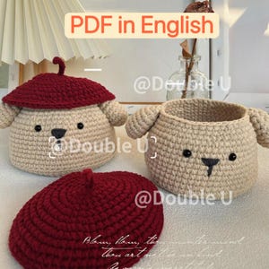 May include: Three handmade crochet items: a beige basket with a dog face, a beige dog-shaped container with a burgundy beret, and a burgundy beret. The text "PDF in English" is visible. The items are handmade.