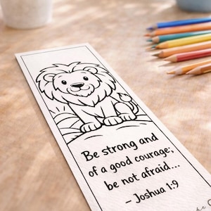 Könnte beinhalten: Weißer Lesezeichen mit einer Schwarz-Weiß-Illustration eines Löwen. Der Text "Be strong and of a good courage; be not afraid... - Joshua 1:9" ist enthalten. Buntstifte und eine blaue Tasse sind im Hintergrund zu sehen.