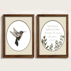 Könnte beinhalten: Zwei gerahmte Kunstdrucke. Der linke Druck zeigt eine Illustration eines Kolibris in einem ovalen Rahmen. Der rechte Druck zeigt den Text "Cast all your anxiety on him because he cares for you. 1 Peter 5:7" in einem ovalen Rahmen, umgeben von grünen Blättern.