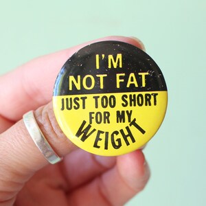 May include: A black and yellow button with the text "I'm not fat, just too short for my weight."