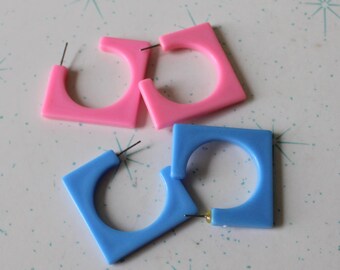 Könnte beinhalten: Drei Paar quadratische Creolen. Zwei Paar sind rosa und ein Paar ist blau.