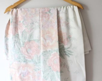 May include: A white and pink floral patterned fabric sheet hanging on a wooden hanger.