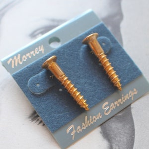 May include: A pair of gold screw-shaped earrings on a blue card with the text "Morrey Fashion Earrings".