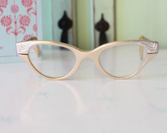May include: A pair of gold-toned cat-eye glasses with silver accents on the temples.