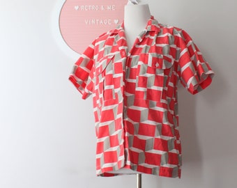 May include: A short-sleeved button-down shirt with a geometric pattern in shades of pink and gray. The shirt is on a mannequin and has a collar.