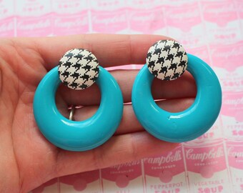 May include: A pair of turquoise hoop earrings with black and white houndstooth patterned centres.