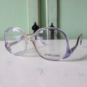 May include: A pair of clear plastic spectacles with purple tinted lenses. The lenses are marked "DEMO LENS".