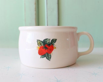 May include: White ceramic mug with a red strawberry design. The mug has a rounded shape and a handle.
