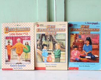 May include: Three paperback books from The Baby-Sitters Club series. The books are titled "Karen's Surprise", "Stacey's Mistake", and "Claudia and the Great Search".