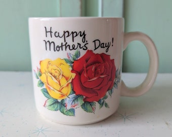 Könnte beinhalten: Eine weiße Keramiktasse mit einem roten und gelben Rosenmuster und dem Text "Happy Mother's Day!"