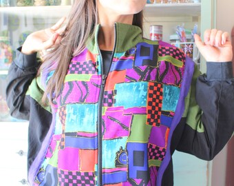 May include: A colorful, geometric patterned jacket with a black zipper and black sleeves. The jacket has a variety of colors, including pink, blue, green, and orange.