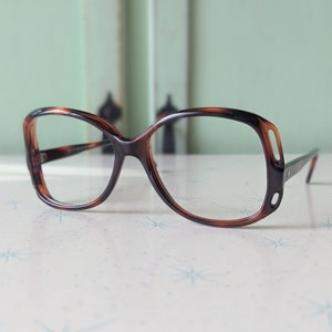 May include: Tortoise shell eyeglasses with a square frame and clear lenses.