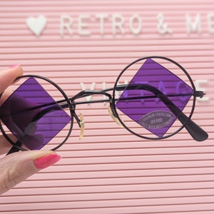May include: Round black framed glasses with purple square lenses. The lenses have a UV400 label.