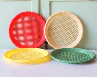 以下が含まれることがあります： 織り模様の入ったプラスチック製のサービングトレイが4つ。トレイは赤、黄、緑、クリーム色です。