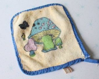 May include: A blue and white mushroom-themed kitchen towel with a blue border and a "NON" label.