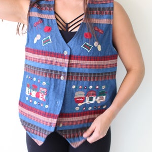 May include: A blue denim vest with red and black plaid stripes and embroidered images of food and kitchen items.