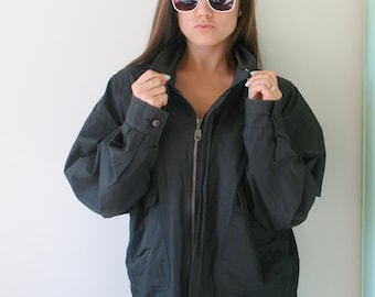 May include: A black zip-up jacket with a high collar and two pockets. The jacket has a silver zipper and a button closure.