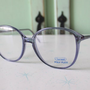 May include: A pair of blue plastic framed glasses with clear lenses. The glasses have a "Charmant Poly Flex" label on the right lens.
