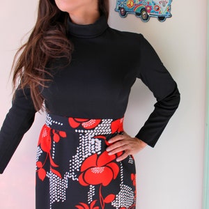 Peut inclure: Une robe noire &agrave; manches longues et col montant. La jupe pr&eacute;sente un motif floral audacieux en rouge et blanc sur fond noir. La robe a une coupe ajust&eacute;e.