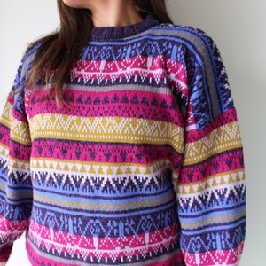 Puede incluir: Un su&eacute;ter a rayas de colores con un patr&oacute;n geom&eacute;trico en tonos de rosa, azul, amarillo y blanco.