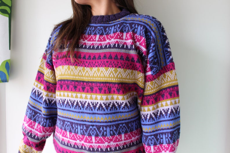Puede incluir: Un su&eacute;ter a rayas de colores con un patr&oacute;n geom&eacute;trico en tonos de rosa, azul, amarillo y blanco.